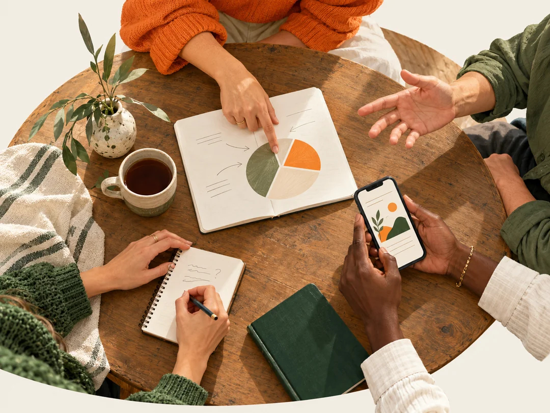 Hands around a shared table point to a portfolio diagram, take notes and explore a smartphone together.